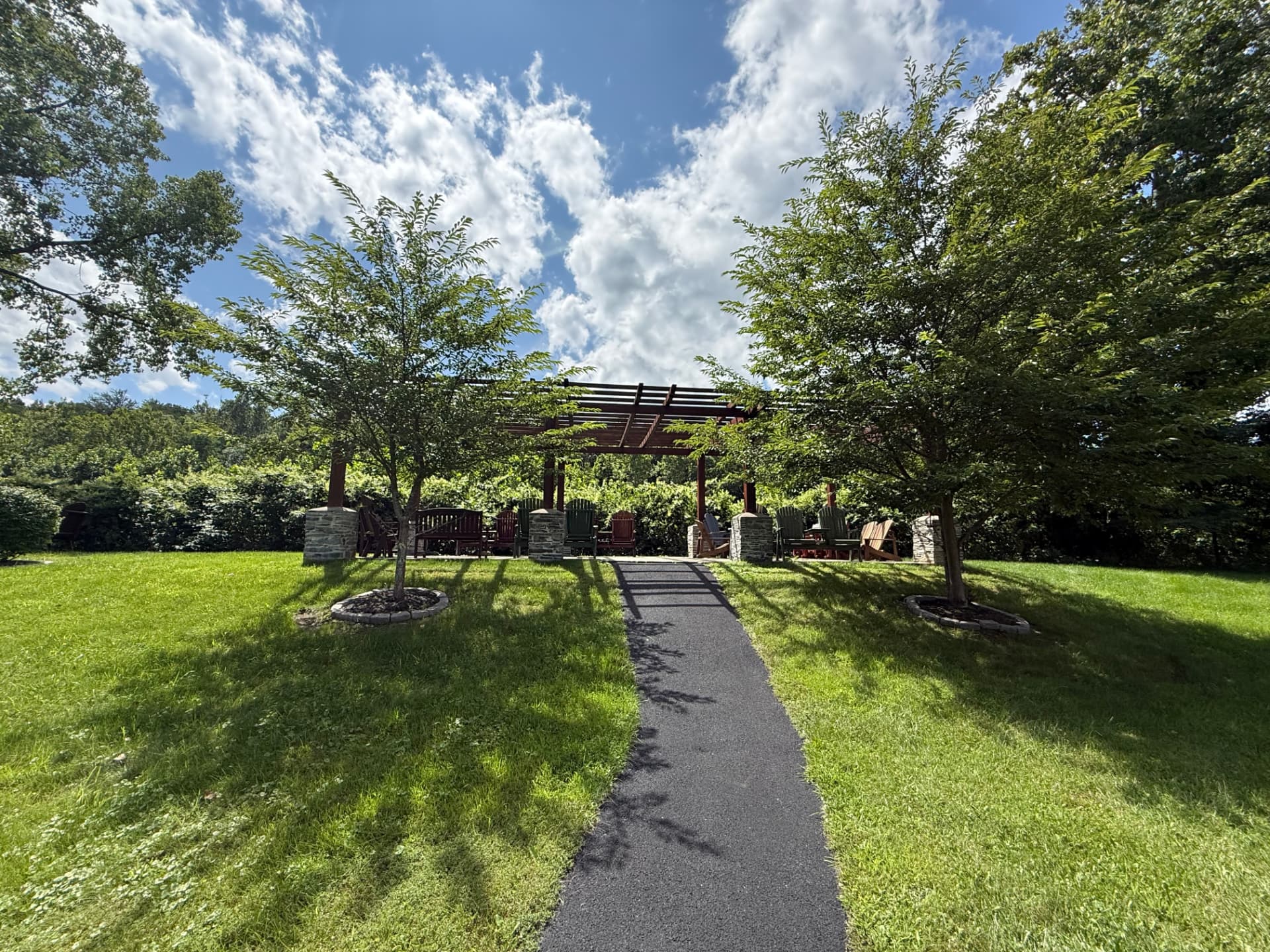 A paved walking path curving through the mature grounds at Tuscany Meadows